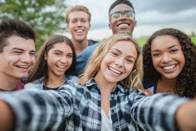Fünf Jugendliche machen ein Gruppenselfie und lächeln in die Kamera