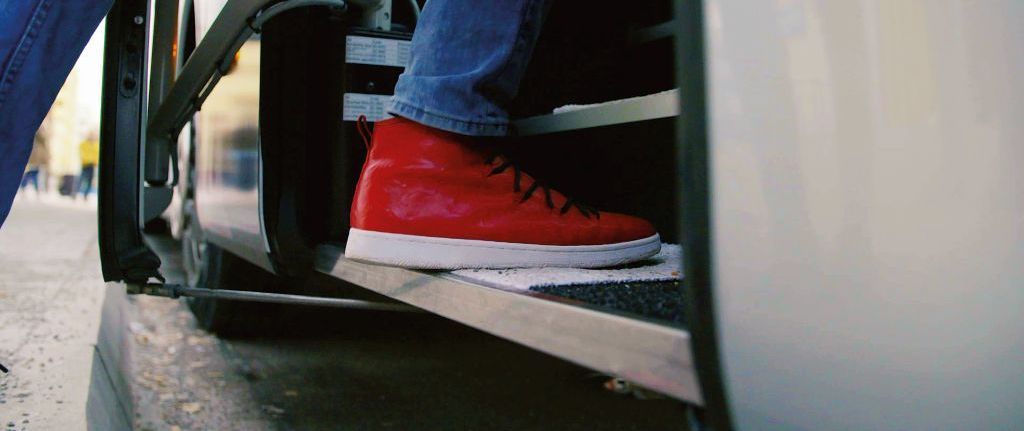 Nahaufnahme von einem Schuh beim Einsteigen in einen Bus.