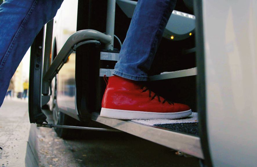 Nahaufnahme von einem Schuh beim Einsteigen in einen Bus.
