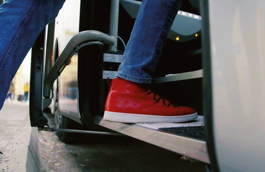 sprungbrett hop-on hop-off Nahaufnahme von einem Schuh beim Einsteigen in einen Bus.