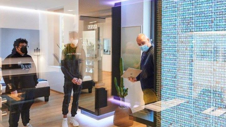 Im Smarten Showroom lernen die Schüler, wie intelligentes Wohnen heute aussieht. © Florian Freund - sprungbrett bayern Die Praktikanten stehen im SmartHome-Showroom, während der Geschäftsführer ihnen die funktionsweise der bunten LED-Wand auf der rechten Seite erklärt.