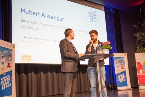 Moderator Sebastian Schaffstein interviewt den Bayerischen Wirtschaftsminister Hubert Aiwanger auf der Bühne.