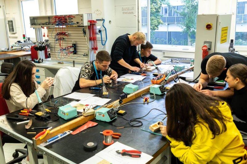 Praktikanten arbeiten unter Anleitung an einem Werkstück.