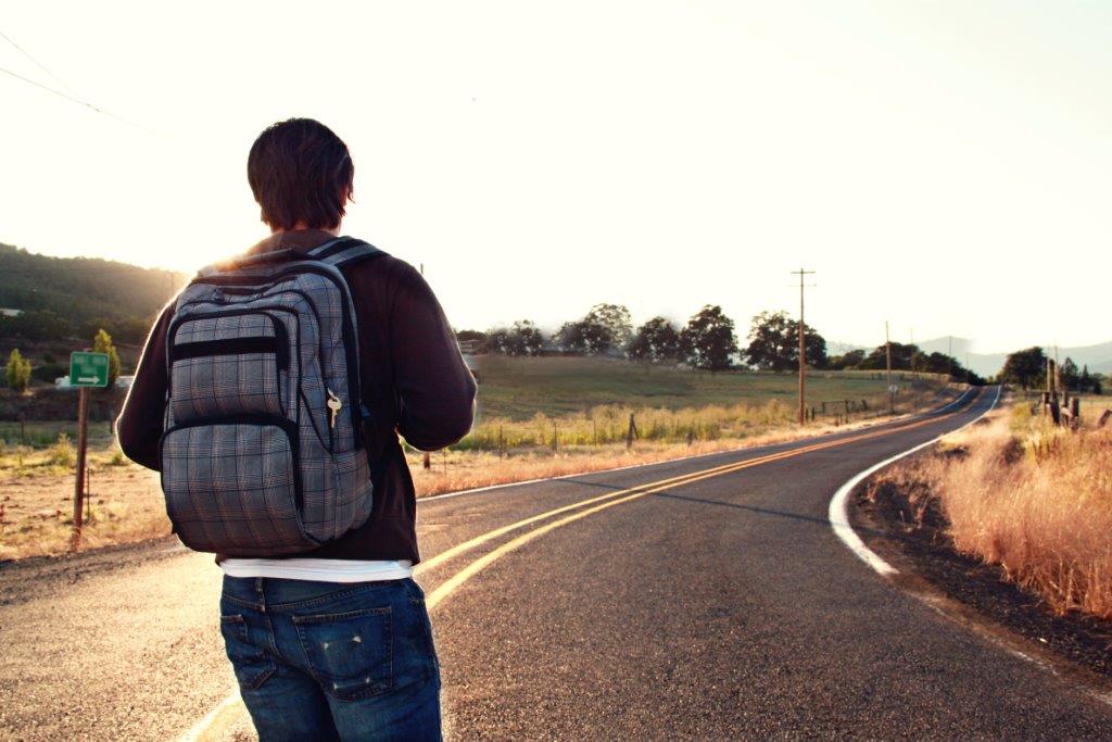 Wanderer mit Rucksack auf einer leeren Landstrasse