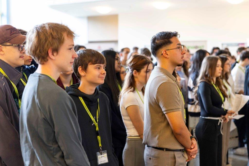 Gruppe von Menschen mit Namensschildern und grünen Lanyards, bei der Veranstaltungseröffnung.