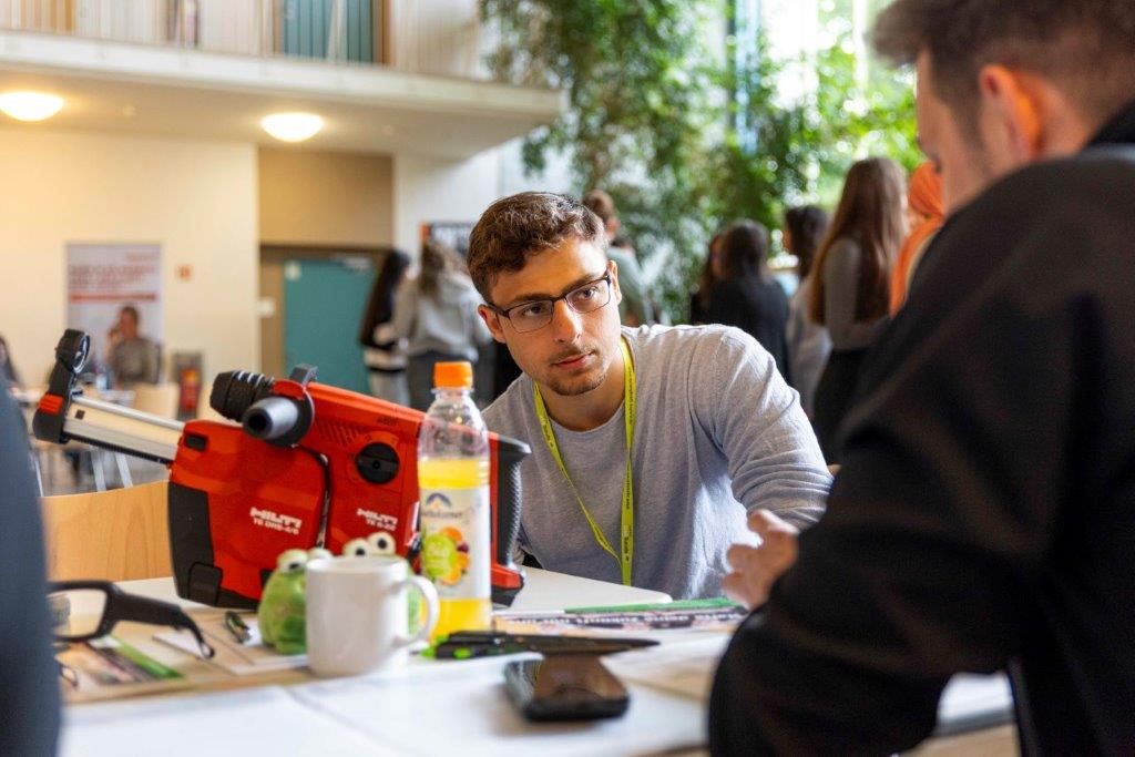 Teilnehmende sitzen an einem Tisch mit Hilti-Werkzeug, Getränken und Unterlagen – Szene vom sprungbrett SPEED DATING in Nürnberg.