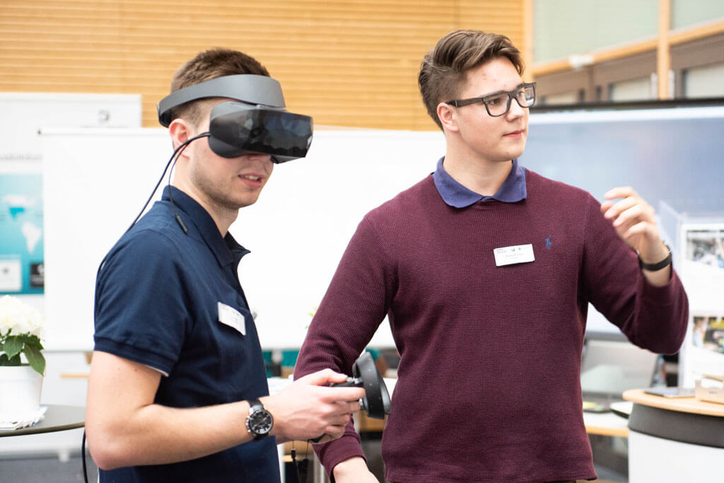 Ein Schüler mit einer VR Brille probiert sich an einem Unternehmensstand aus.