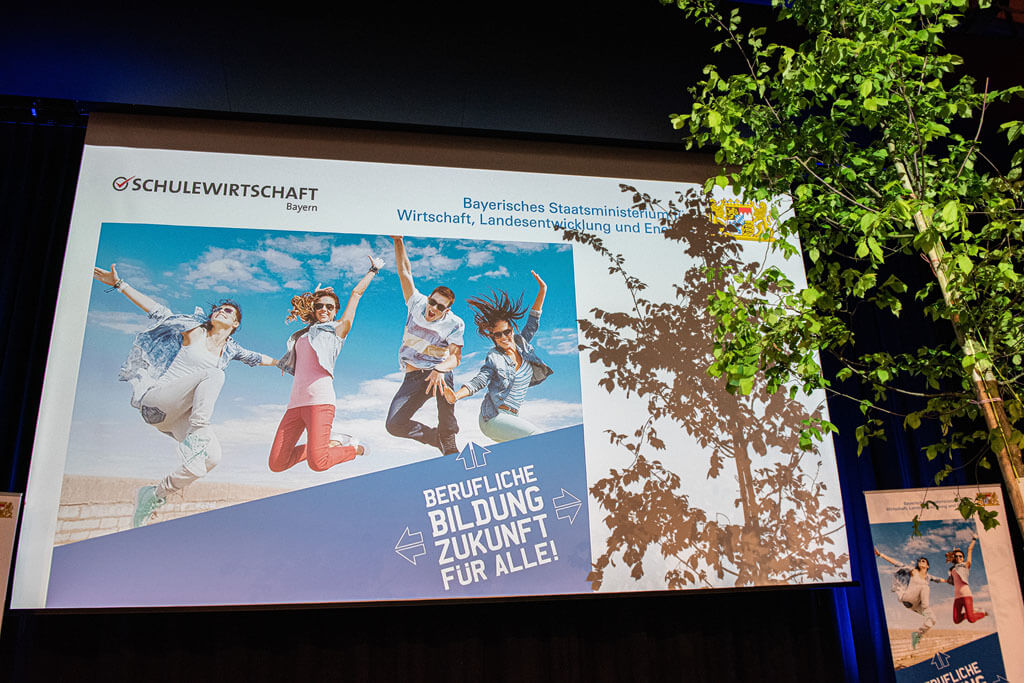 Die Bühnenleinwand mit dem Logo der Veranstaltung "Berufliche Bildung - Zukunft für alle!" mit dem Baum des Jahres 2019 - der Flatterulme.