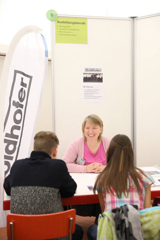 Schülerin und Schüler im Gespräch am Stand der Goldhofer AG.