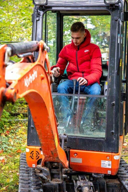 Ein Praktikant arbeitet mit einem Bagger.